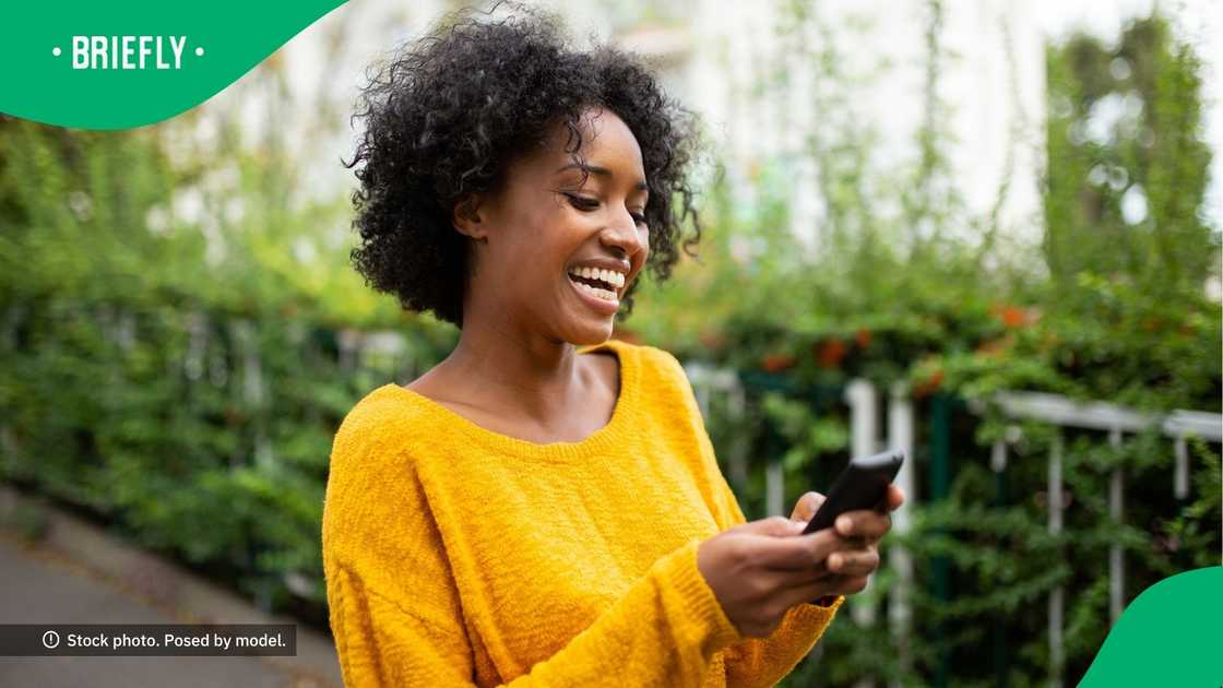 A woman smiling at her phone. A woman smiling at her phone.