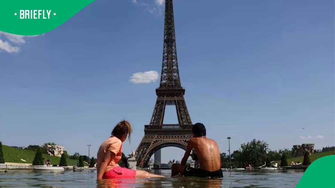 A man and a woman sought relief from the extreme temperatures by wading in a water basin near the iconic French landmark A man and a woman sought relief from the extreme temperatures by wading in a water basin near the iconic French landmark