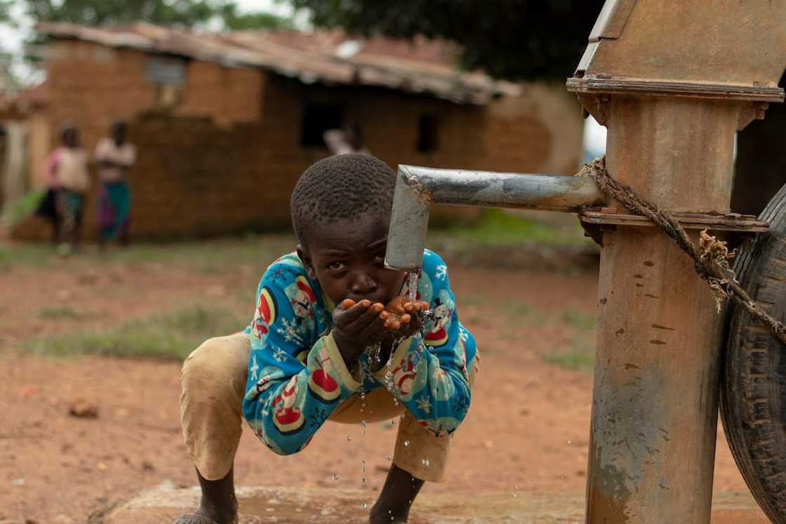 A little boy drinking water from a borehole fitted with a pump A little boy drinking water from a borehole fitted with a pump