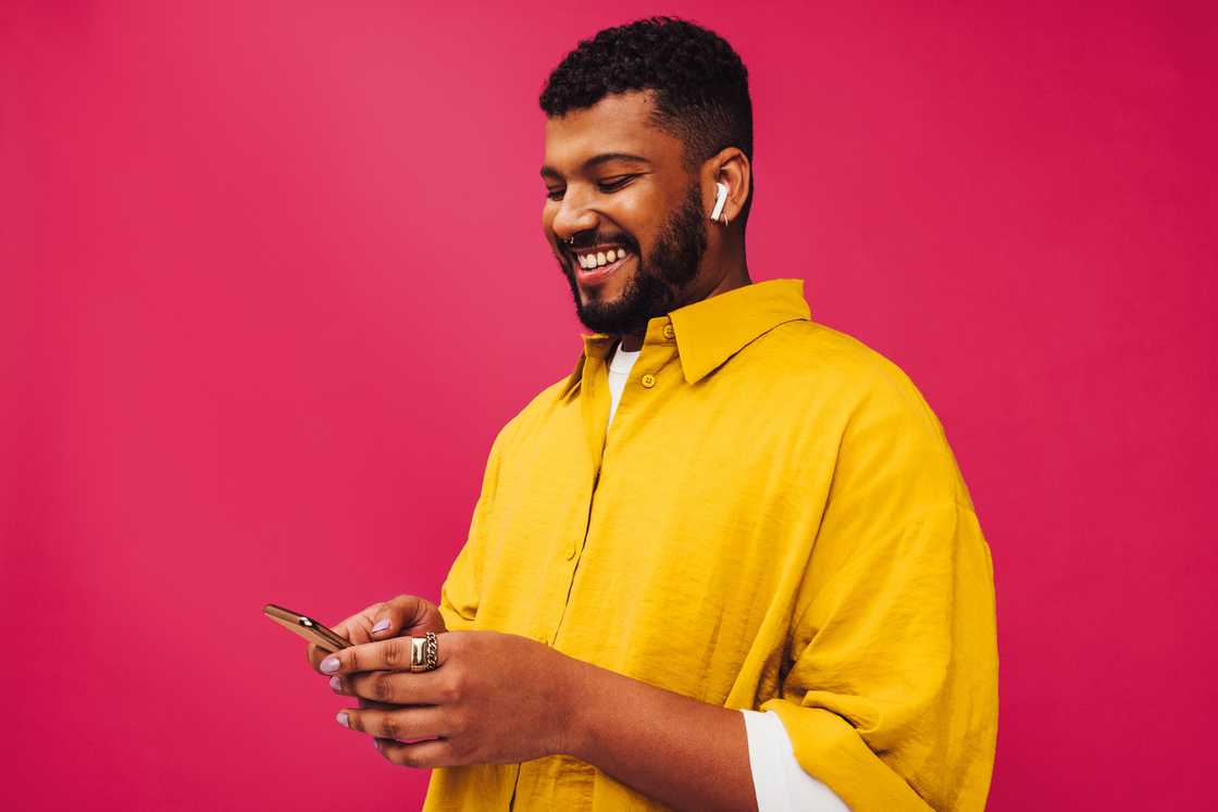 A man smiling at his phone. A man smiling at his phone.