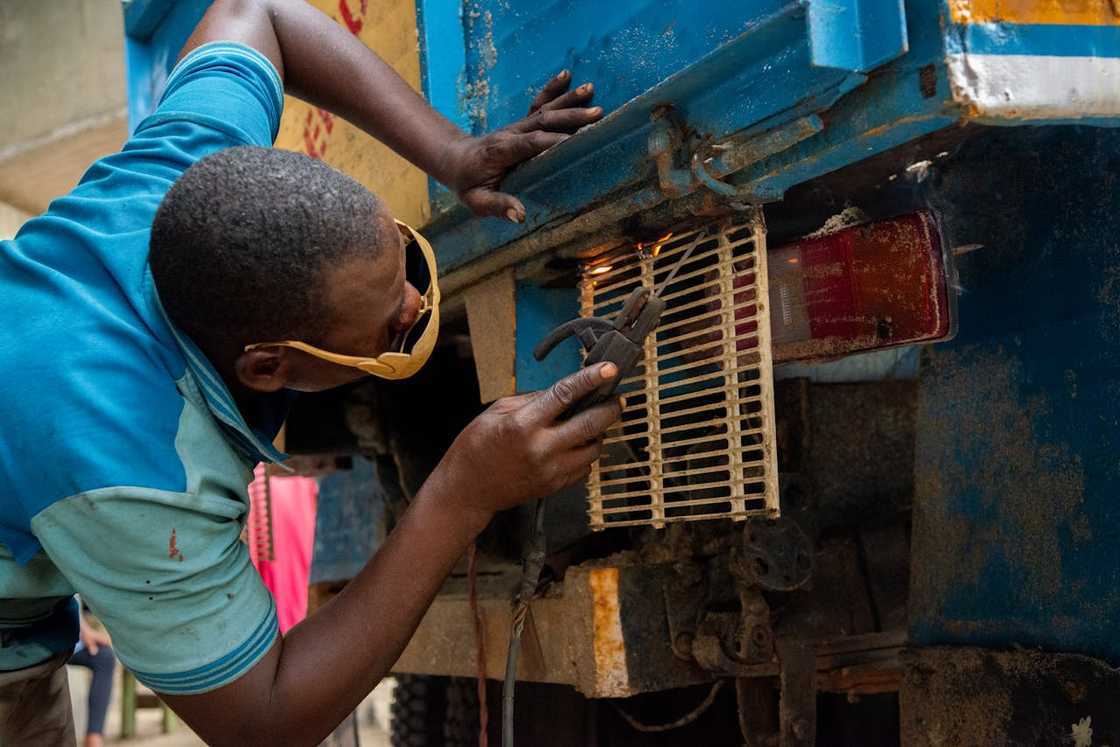 A mechanic repairs the back of a truck using tools. A mechanic repairs the back of a truck using tools.