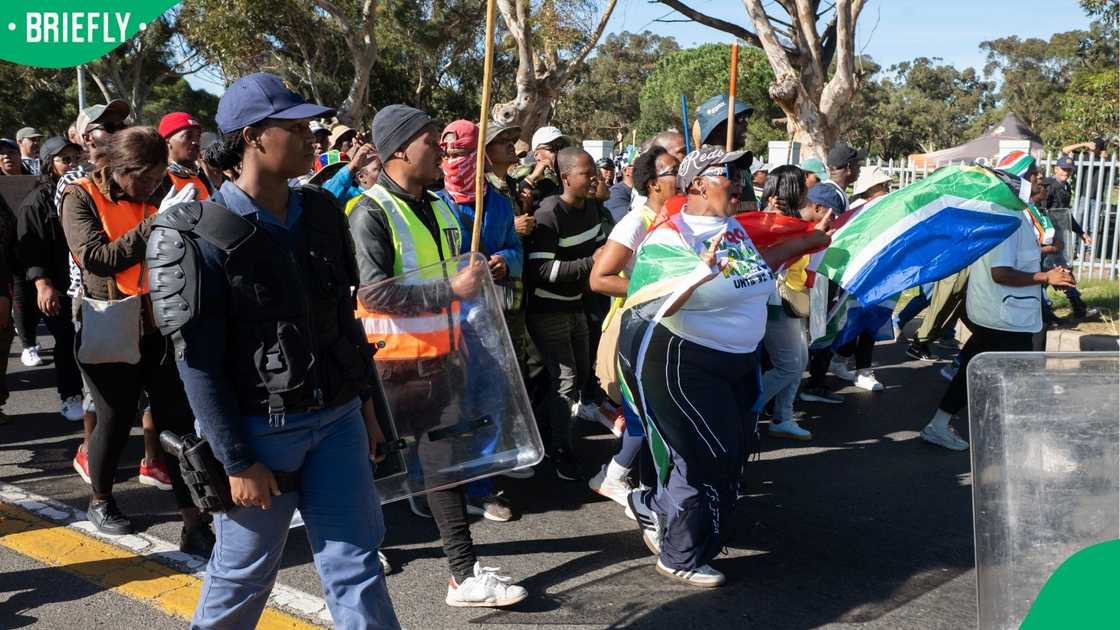A group of people, many carrying sticks and clubs, take part in a protest against illegal immigrants organised by March and March