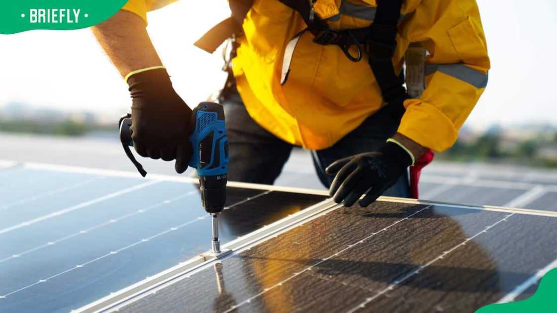 An electrician installing photovoltaic blue solar modules An electrician installing photovoltaic blue solar modules