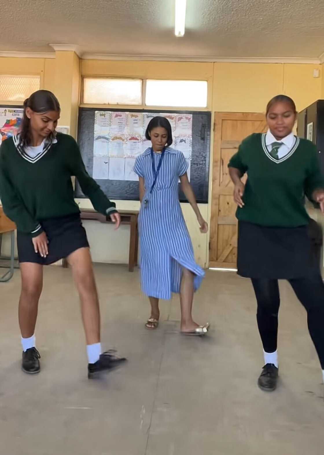 A teacher dancing in a classroom with her two female learners. A teacher dancing in a classroom with her two female learners.