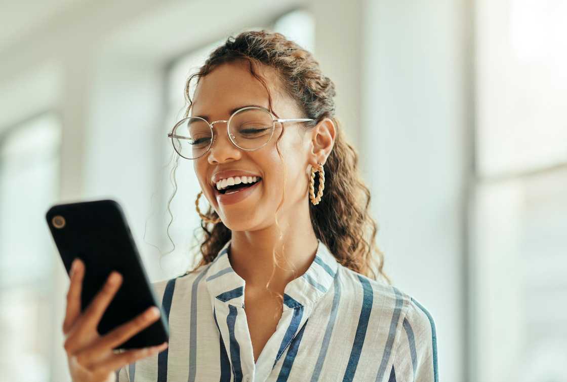A woman laughs at her phone. A woman laughs at her phone.