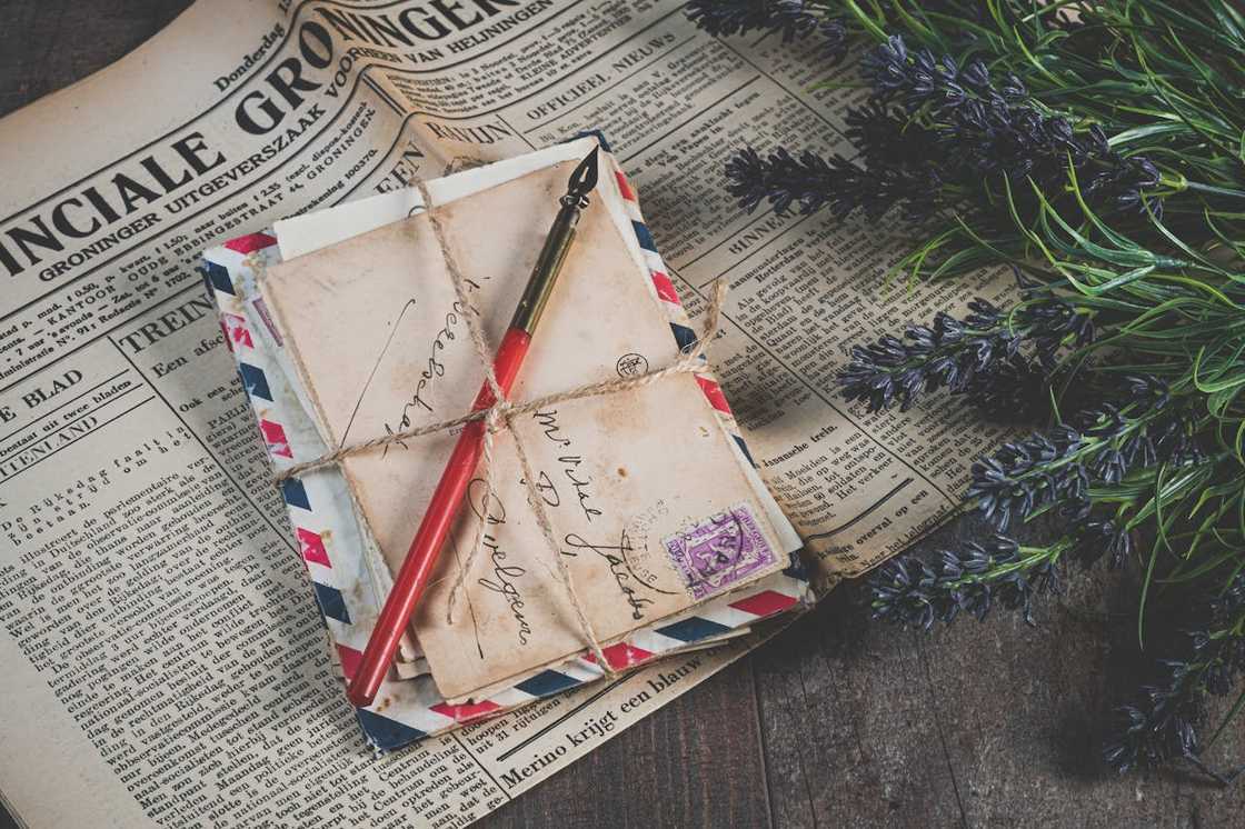 A bundle of old letters tied with a string on a newspaper.