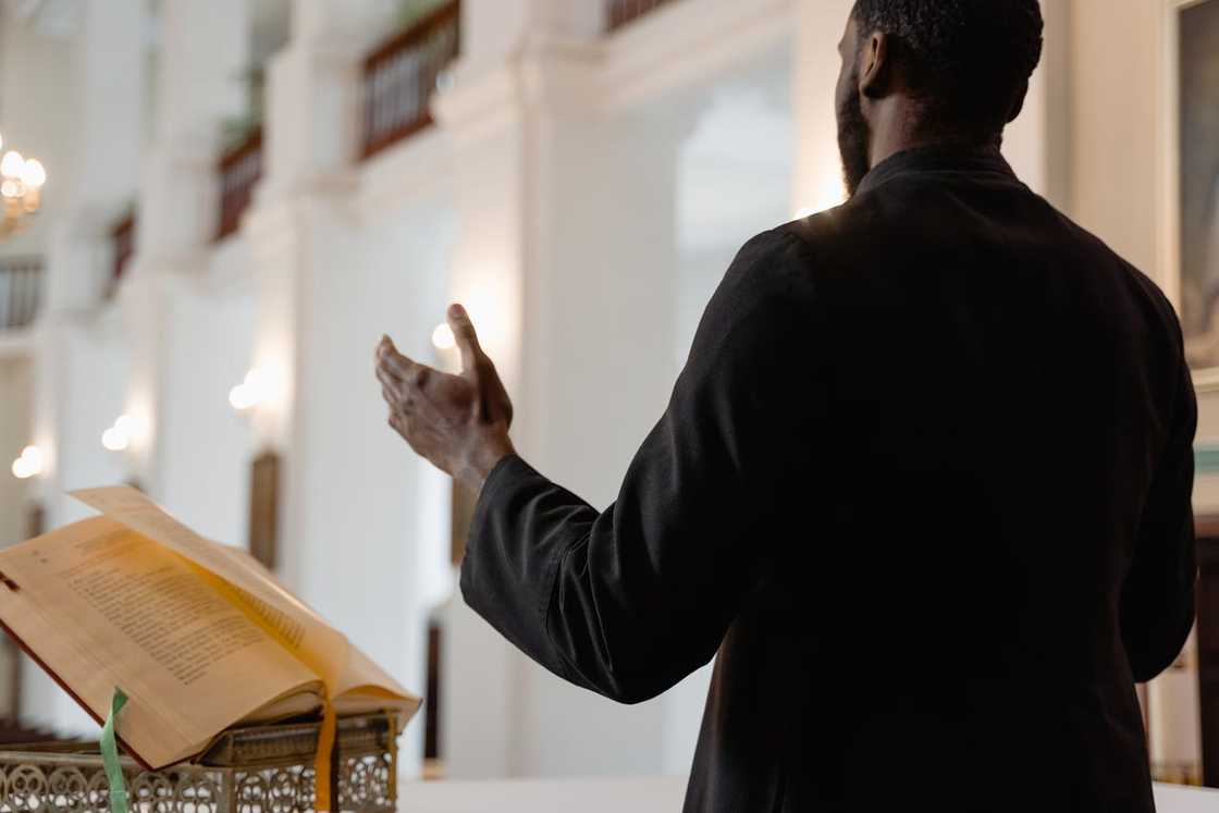 A priest preaching from a lectern inside a large church hall. A priest preaching from a lectern inside a large church hall.
