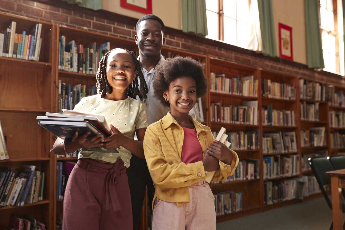 Portrait of smiling students standing with professor in library at school.