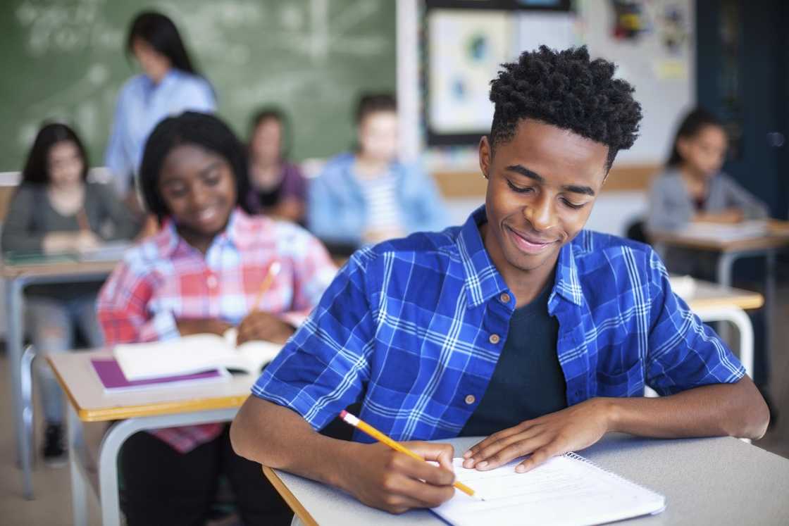 A student writing while studying in classroom