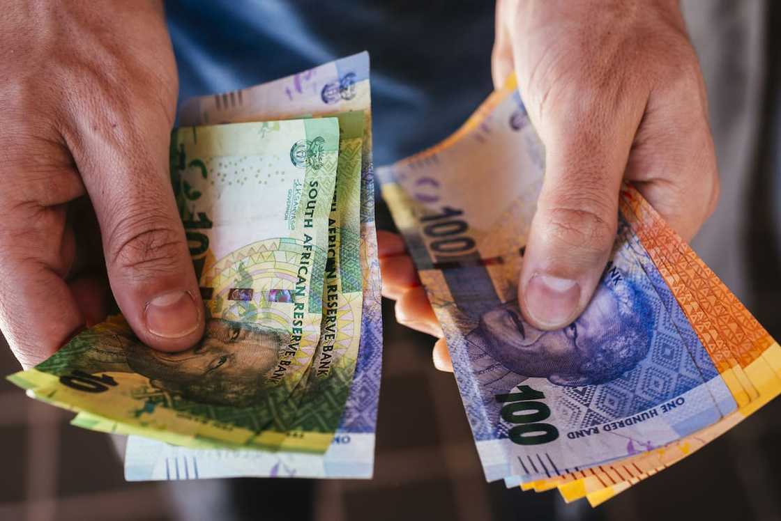 A person holding a collection of mixed denomination South African rand banknotes in Johannesburg A person holding a collection of mixed denomination South African rand banknotes in Johannesburg