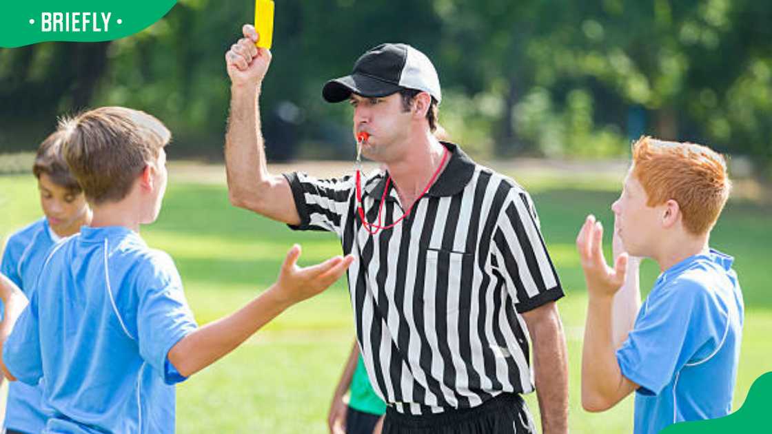 A referee holds up a yellow card during soccer game