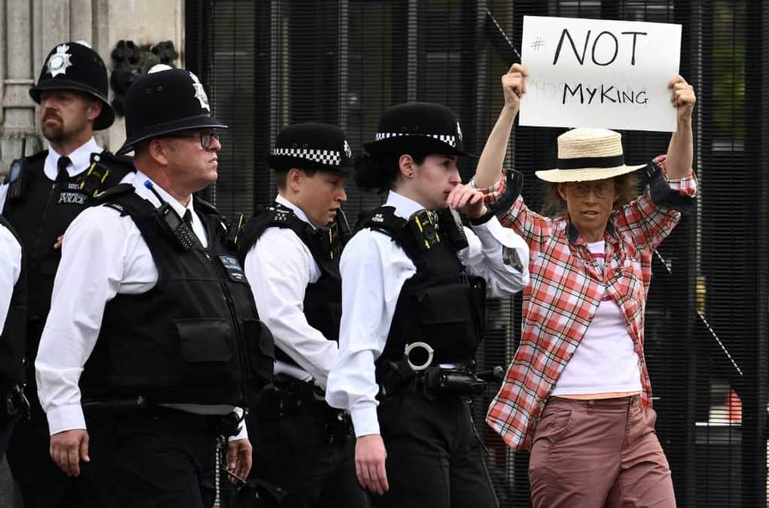 One protester was ushered away from the UK parliament for holding up a sign against King Charles III