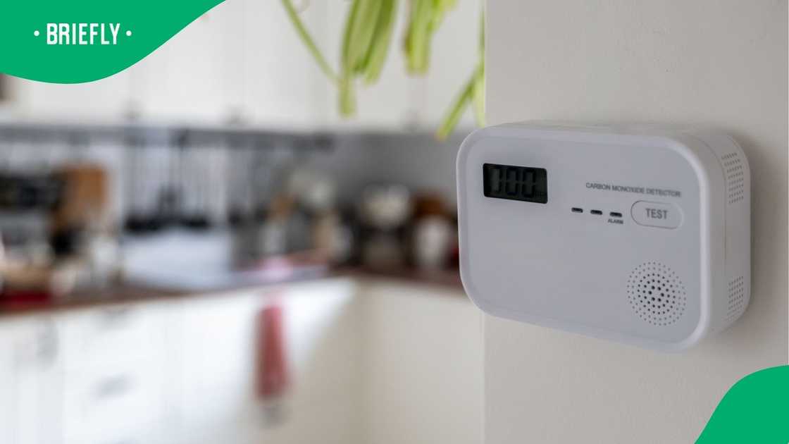 A white carbon monoxide detector positioned on kitchen wall. A white carbon monoxide detector positioned on kitchen wall.