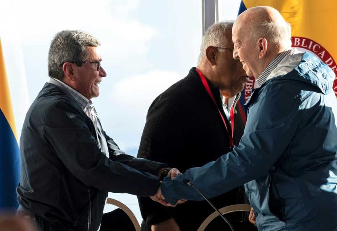 National Liberation Army (ELN) Commander Pablo Beltran (left) and government representative Otty Patino shake hands after announcing the results of the peace talks