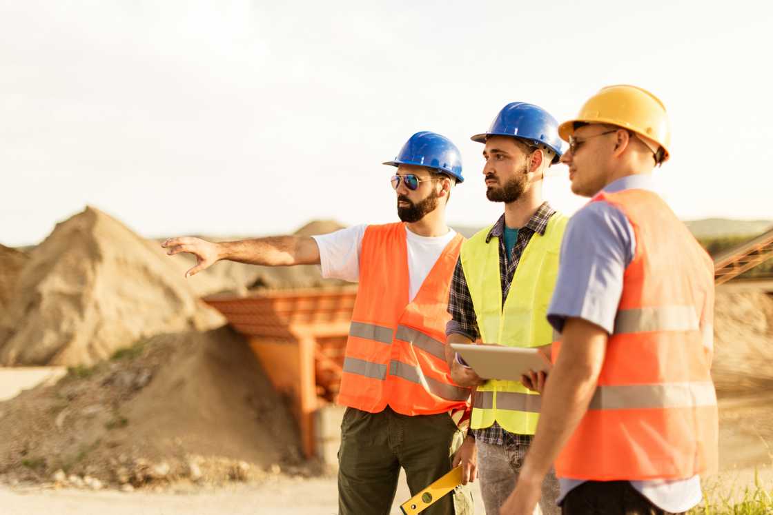 Three experts with hard hats on construction site.