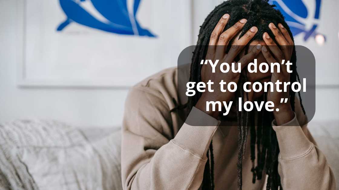 A man sitting on a sofa holding his head in distress.