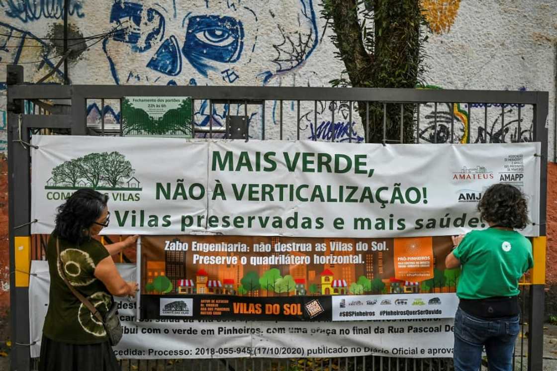 Activists from the Pro Pinheiros association place a banner on a gate that reads "More green, not verticalization" in the Pinheiros neighborhood, Sao Paulo, Brazil, on September 5, 2023 Activists from the Pro Pinheiros association place a banner on a gate that reads "More green, not verticalization" in the Pinheiros neighborhood, Sao Paulo, Brazil, on September 5, 2023