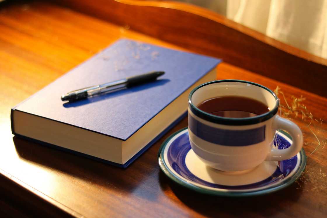 A closed minute book and teacup on a table.