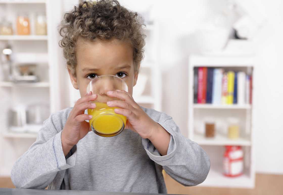 A toddler drinking juice. A toddler drinking juice.