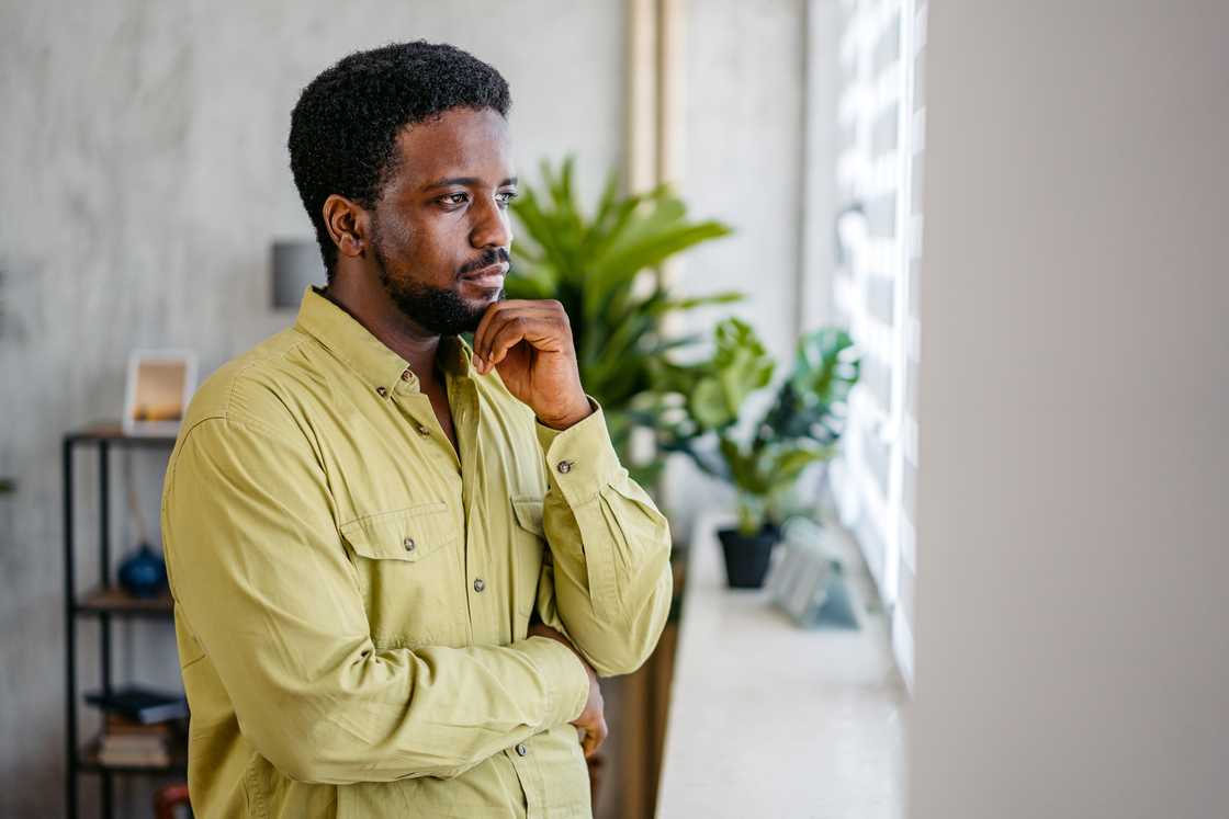 A man looking out the window at home.