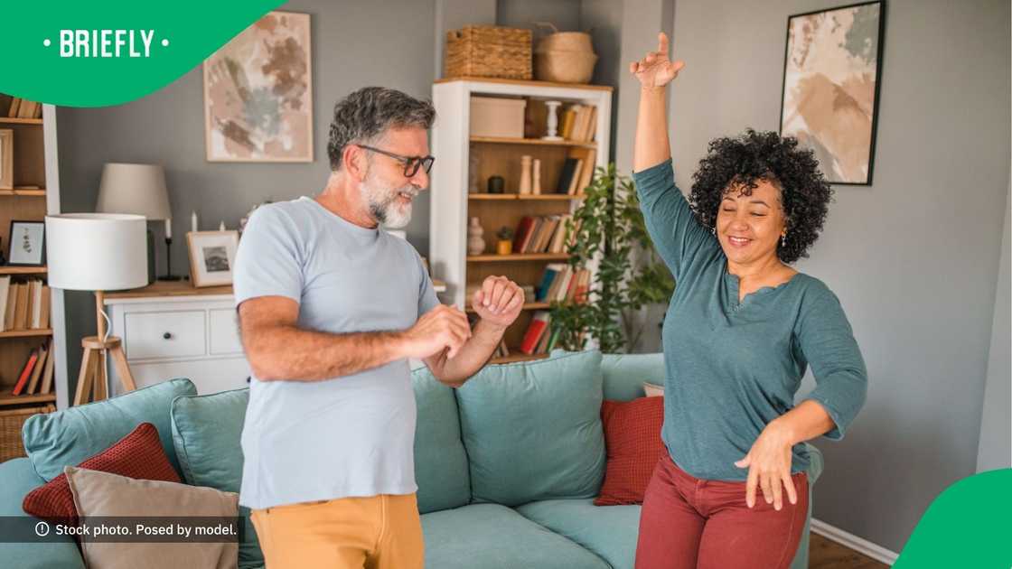 A couple is seen dancing in the living room.