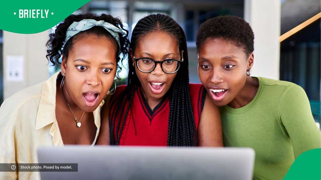 A group of surprised women looking at a laptop screen. A group of surprised women looking at a laptop screen.