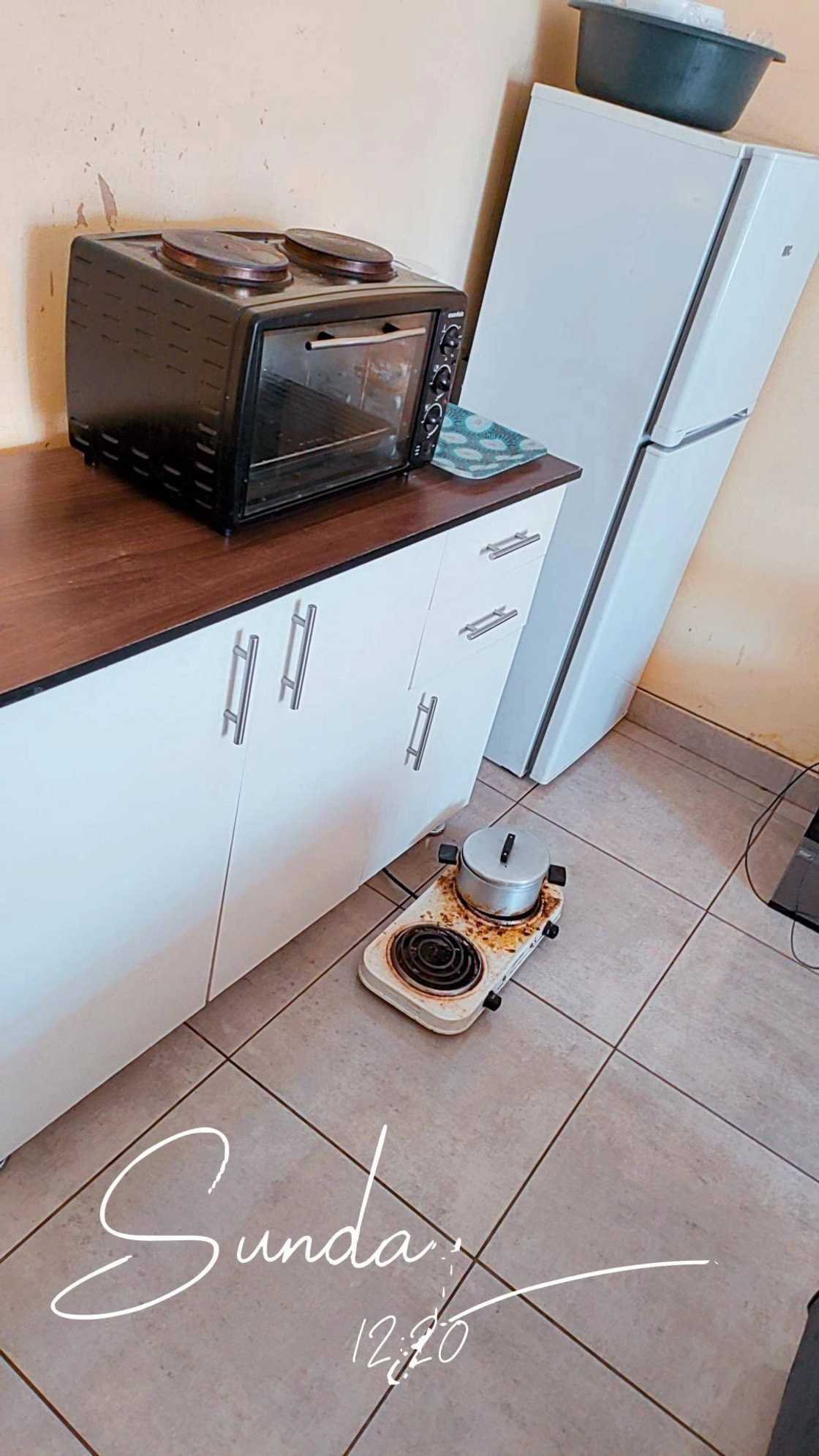 The kitchen has a cupboard, fridge and a stove.