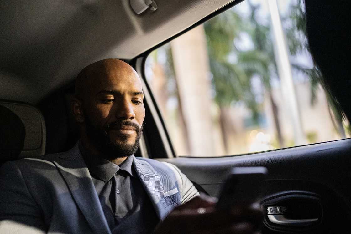 A mid adult man using the mobile phone in a car
