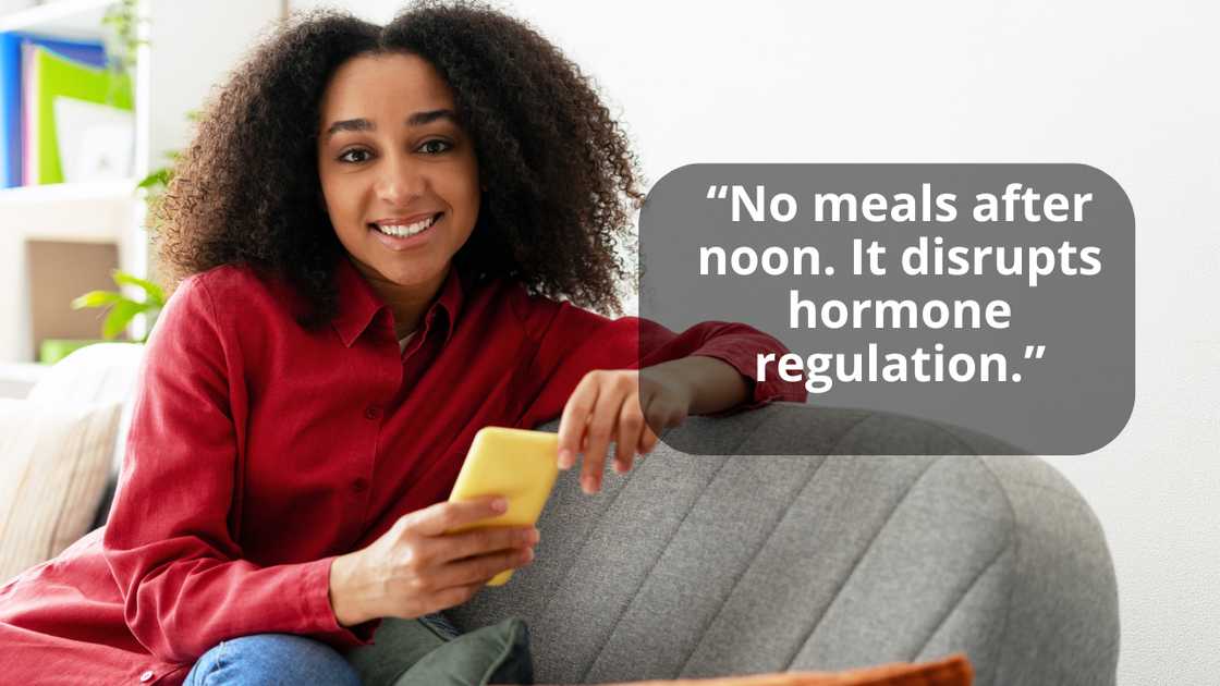 A woman holding mobile phone while sitting on sofa at home