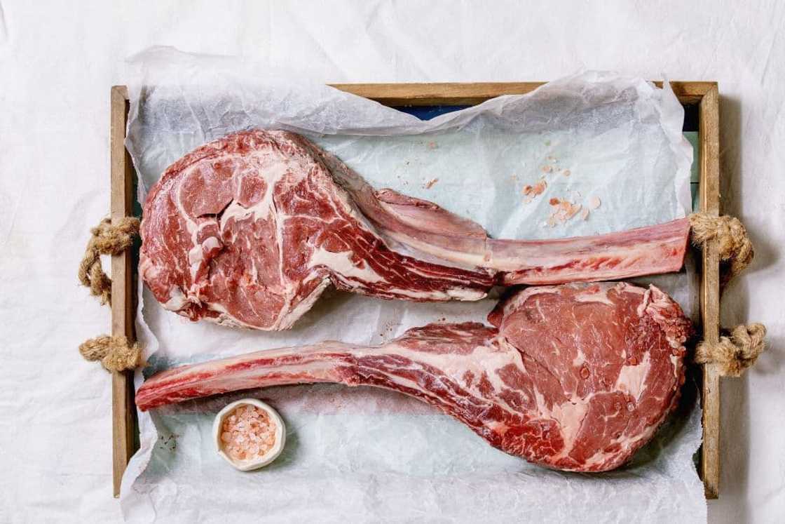 Raw Black Angus beef tomahawk steaks on bones.