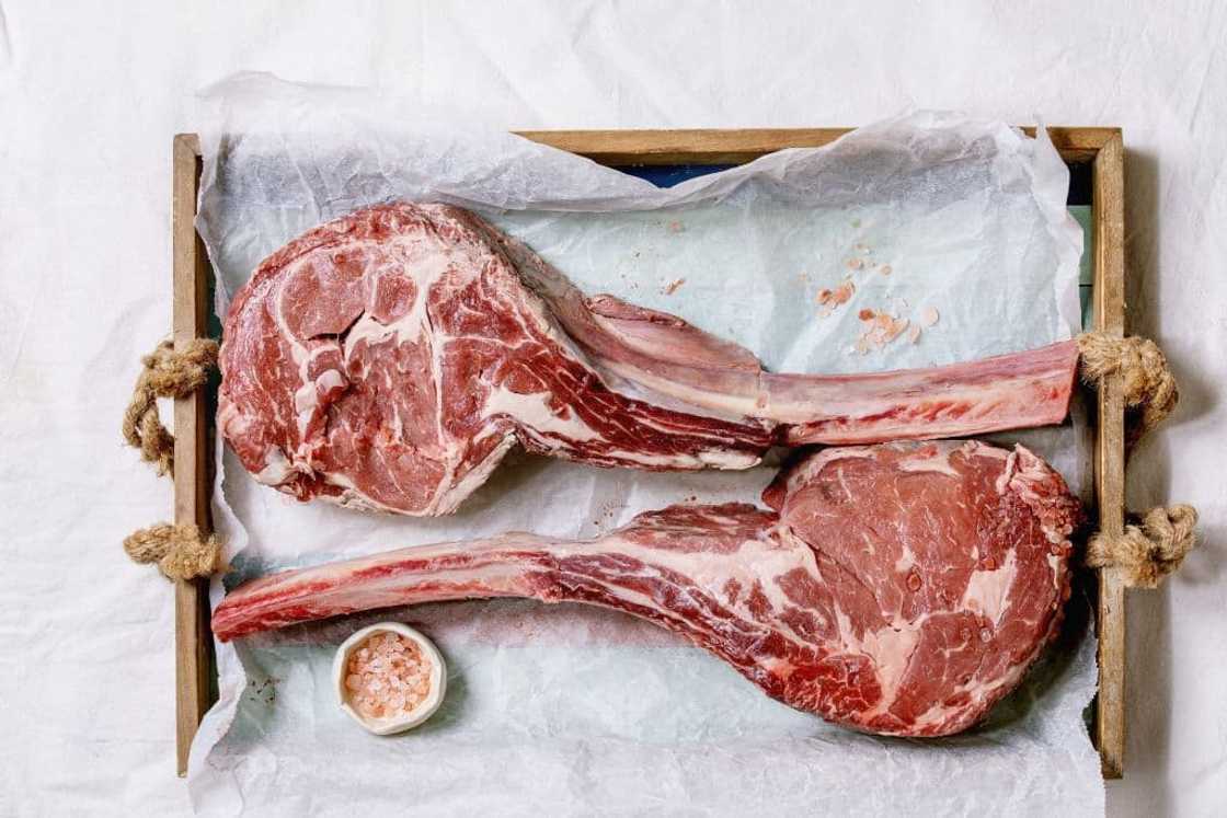 Raw Black Angus beef tomahawk steaks on bones. Raw Black Angus beef tomahawk steaks on bones.