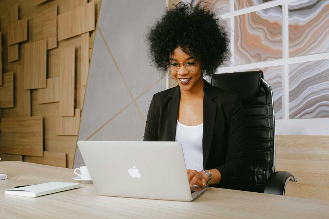 A woman wearing a black blazer using MacBook A woman wearing a black blazer using MacBook