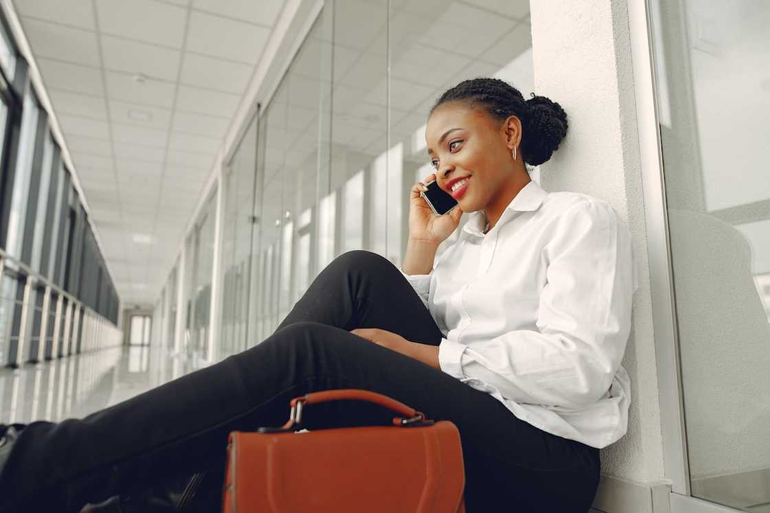 A woman in a white shirt and black pants making a phone call A woman in a white shirt and black pants making a phone call