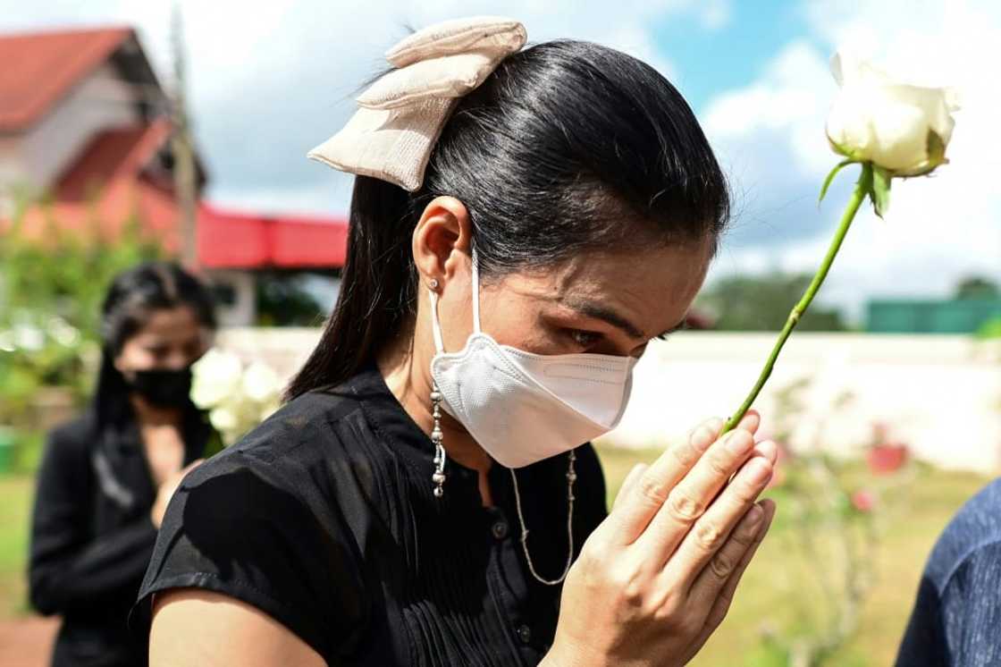 Mourners lay single white roses on the steps of the Thai nursery where nearly two dozen children were murdered