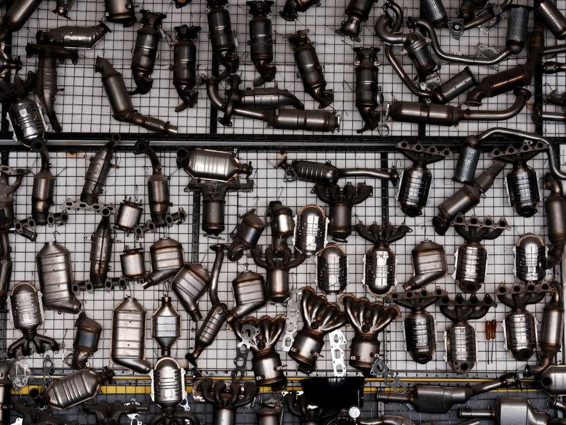 Assorted car exhaust and catalytic converter parts arranged on a wall.