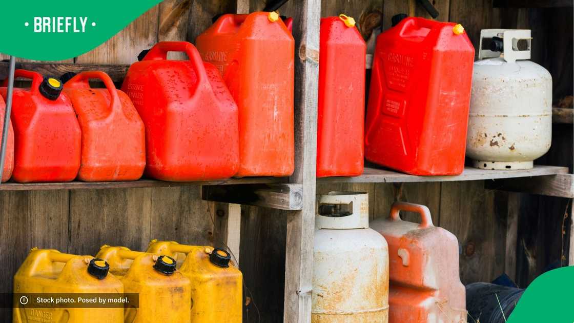A group of jerry cans and propane tanks sit on shelves in a wooden shed A group of jerry cans and propane tanks sit on shelves in a wooden shed