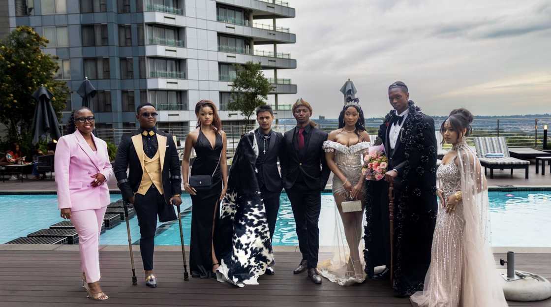 A group photograph of eight attendees posing on the rooftop pool terrace of the Sandton Hotel during the 2025 MET Gala for Matriculants.