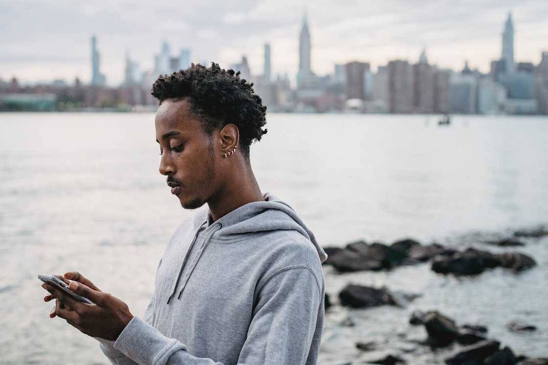 A man in a grey hoodie using a smartphone