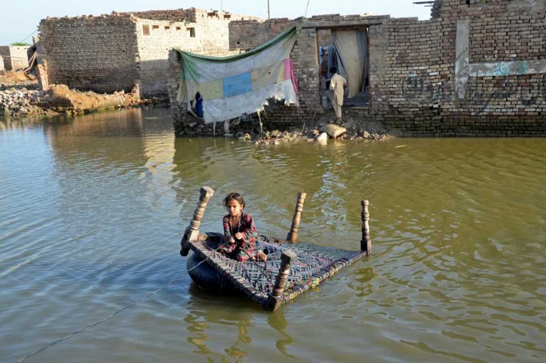 A girl sits on a cot as she crosses a flooded street at Sohbatpur in Jaffarabad district of Balochistan province on October 4, 2022 A girl sits on a cot as she crosses a flooded street at Sohbatpur in Jaffarabad district of Balochistan province on October 4, 2022