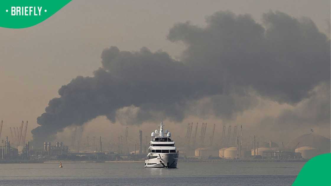 A sailing yacht with smoke seen in the background. A sailing yacht with smoke seen in the background.