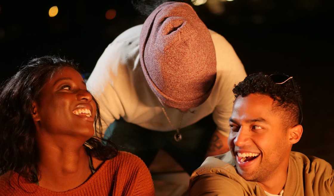 Friends laugh together around a bonfire.