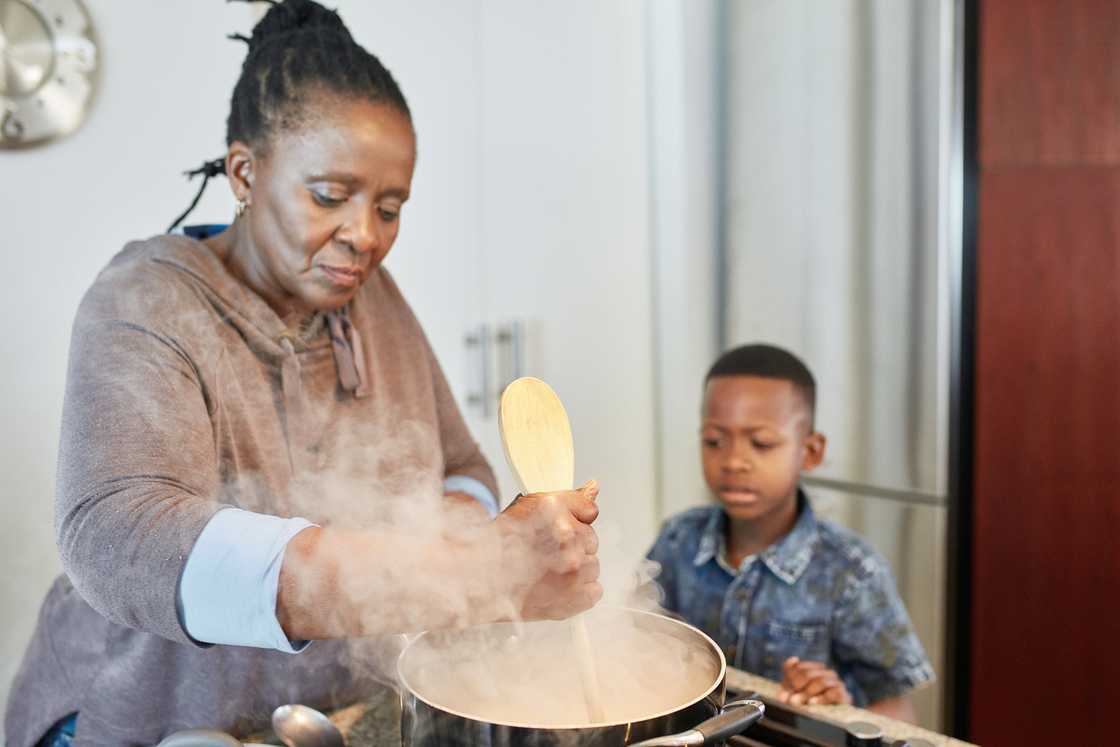 A young boy watching his grandmother make pap.