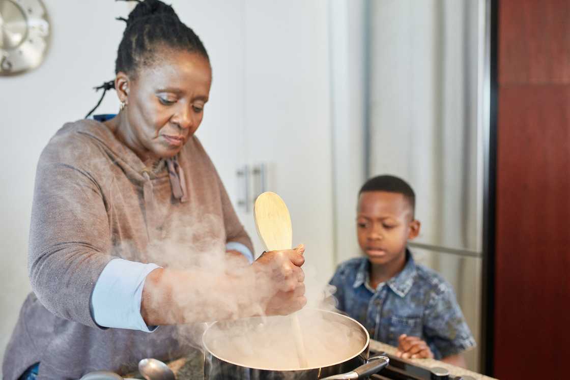 A young boy watching his grandmother make pap. A young boy watching his grandmother make pap.