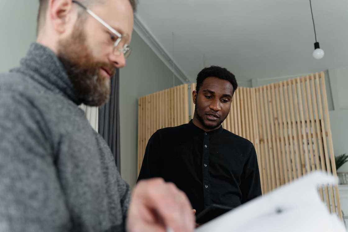 Two men reviewing documents together in an office. Two men reviewing documents together in an office.