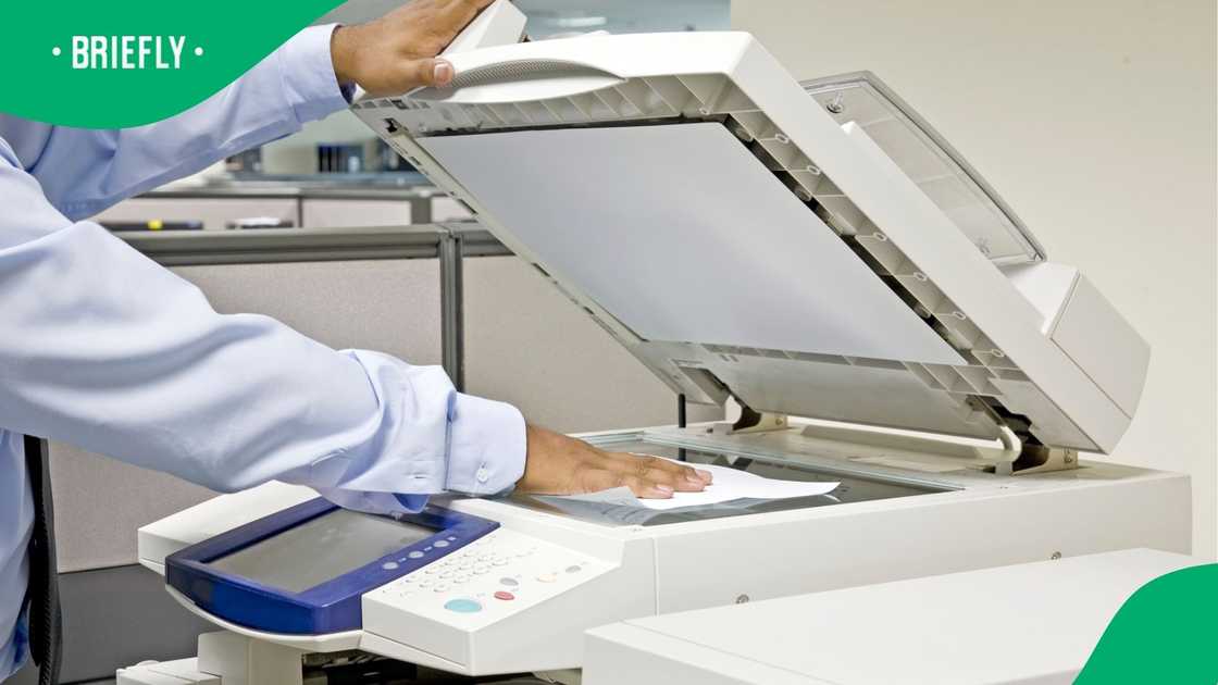 A person busy scanning physical documents on a printer to digitise it.