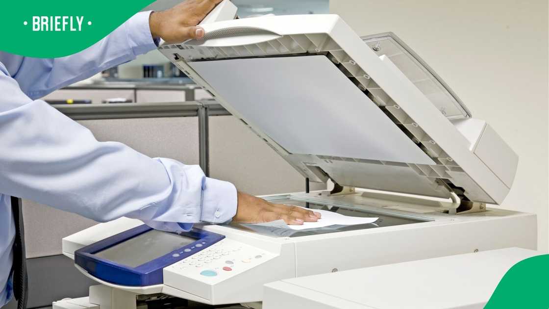 A person busy scanning physical documents on a printer to digitise it. A person busy scanning physical documents on a printer to digitise it.