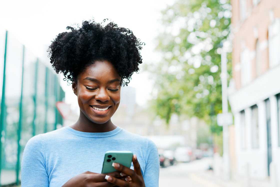A woman smiling at her phone. A woman smiling at her phone.