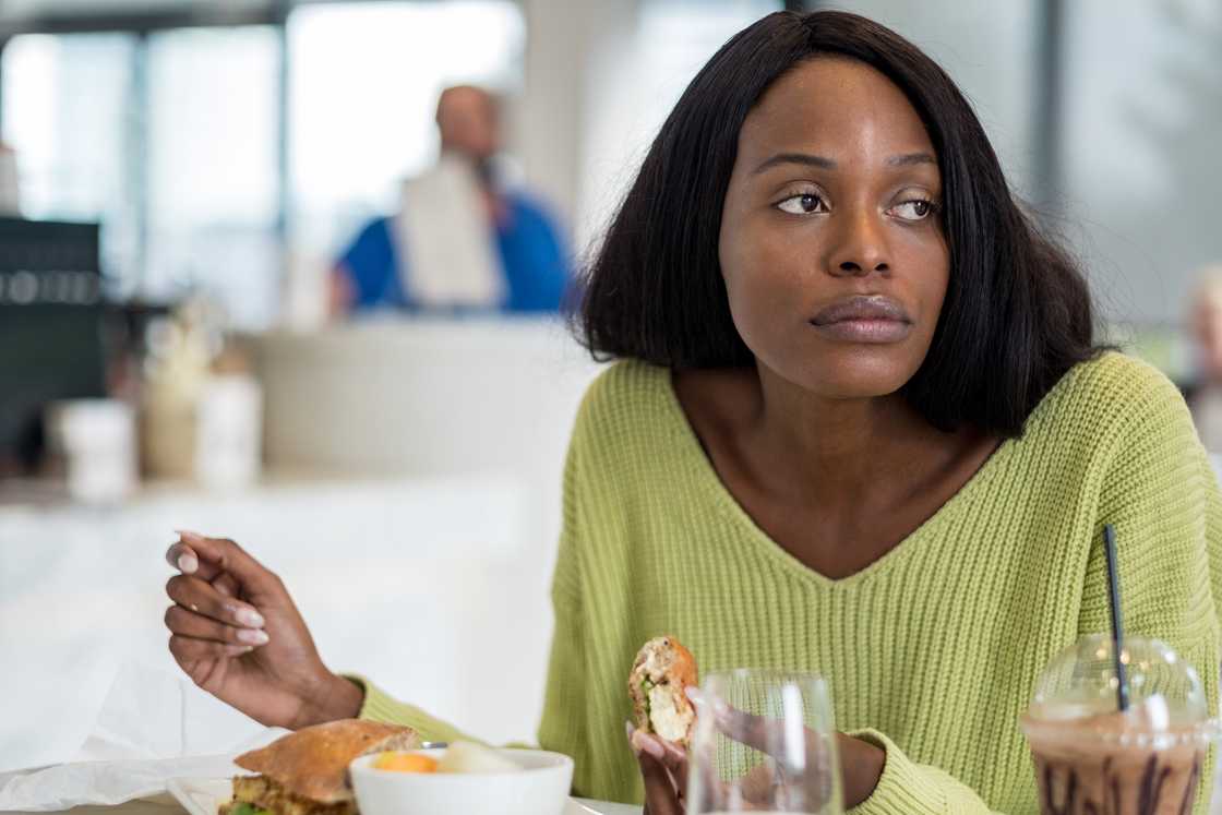 A woman with a troubled expression at a café. A woman with a troubled expression at a café.