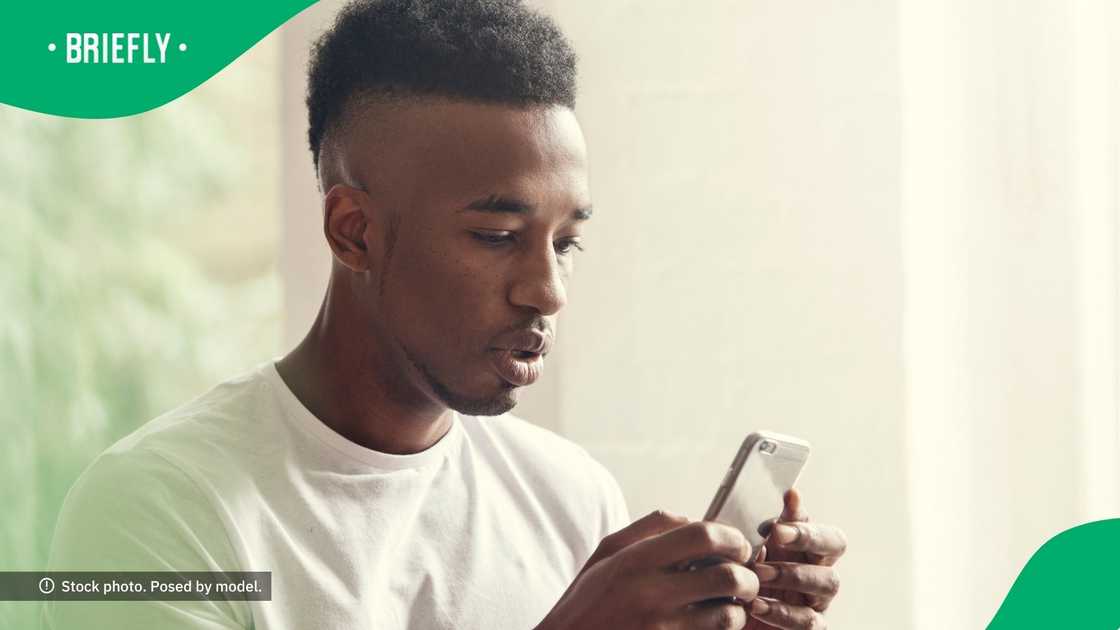 A young man texting on his phone. A young man texting on his phone.