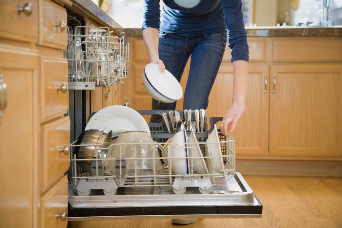 Teenage girl putting dishes in dishwasher, low section Teenage girl putting dishes in dishwasher, low section